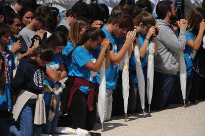 Uno fieles cristianos rezan de rodillas durante la misa, el 13 de mayo.