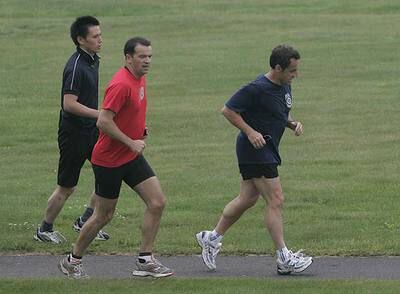 El presidente francés, Nicolas Sarkozy, corre seguido por sus guardaespaldas en un campo de golf en Toyako.