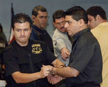 Un policía retira las esposas al sacerdote católico Minor Calvo (izda), al ingresar a la sala 12 de los Tribunales de Justicia, en San Jose, el 6 de diciembre de 2005.