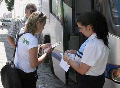 Dos viajeros, en la puerta de uno de los autobuses contratados por Renfe.