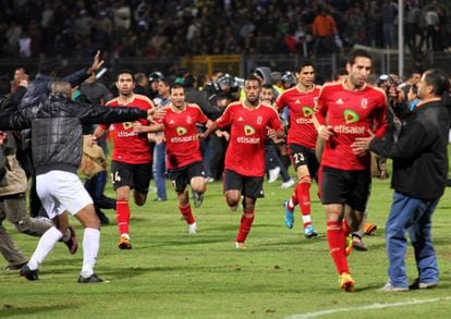 Jugadores del equipo Al Ahli escapan del campo en el momento en que fanáticos del equipo contrario, Al Masri se lanzaron al campo. Cientos de personas resultaron heridas en el enfrentamiento entre los hinchas de ambos equipos.