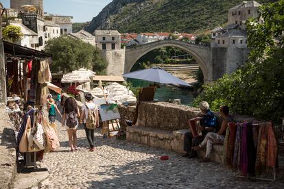 Mostar vive un momento especial. Este verano se celebra el 20º aniversario de la reconstrucción del puente Stari Most, una excusa perfecta para conocer la ciudad, favorita de mochileros y amantes de los Balcanes, que por fin se convierte en un destino para algo más que una visita rápida de un día. Su casco antiguo medieval, salpicado de alminares, y el famoso puente, seguirán siendo la gran atracción, pero además hay festivales de arte, artesanía y música.
Después de pasear por las calles adoquinadas del casco antiguo, entre mezquitas, bazares y cafés, se puede cruzar el rio Neretva, para descubrir una nueva cara de Mostar en Španjolski Trg, el barrio occidental de la ciudad, donde el Street Arts Festival Mostar (SAFMO) encarga a artistas y diseñadores la creación de enormes murales. Con la intención de reconstruir el espíritu comunitario y dejar atrás los conflictos de antaño, SAFMO invita a creativos locales e internacionales a pintar obras políticas, coloridas y emotivas. Estos enormes murales decoran edificios abandonados, bloques residenciales y zonas urbanas (en las que aún se ve el impacto de la metralla de los bombardeos durante las guerras yugoslavas) y ayudan a regenerar el barrio. SAFMO inaugura una nueva obra cada verano, pero la mayoría de las obras de arte se pueden ver todo el año. La plaza Španjolski Trg también alberga el Mostar Summer Fest, un festival de tres días con bandas de todos los Balcanes; y en diciembre se llena de puestos de comida y artesanía con el mercado navideño.
Pero el protagonista este año será el puente, destruido en 1993 y reinaugurado el 23 de julio del 2004 en todo su esplendor. Este verano celebrará su 20 aniversario por todo lo alto y para ver un gran espectáculo es buena idea visitar la ciudad el último fin de semana de julio, durante el Mostar Bridge Jumping Festival, heredero de una tradición local con siglos de historia.