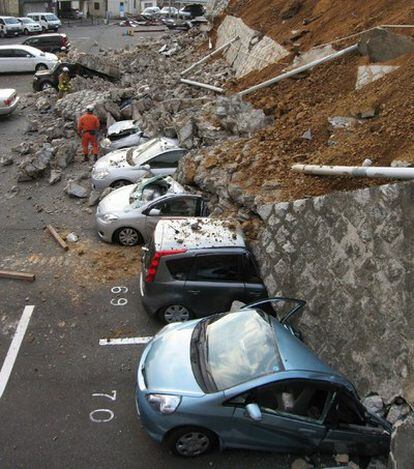 Coches aplastados por un muro derrumbado en un aparcamiento en la ciudad de Mito, en la provincia de Ibaraki, después del terremoto que sacudió Japón hoy viernes