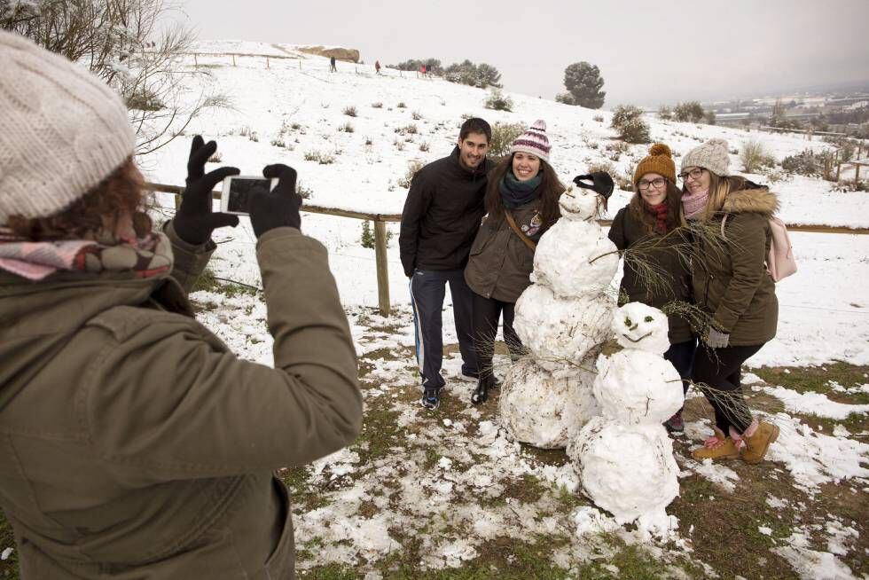 Un grupo de jóvenes se fotografían junto a un muñeco de nieve.