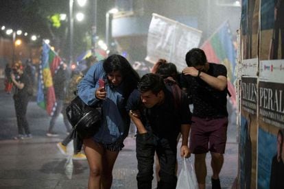 La gente huye de un cañón de agua utilizado por la policía antidisturbios durante una manifestación contra Kast en Santiago este viernes, dos días antes de la segunda vuelta de las elecciones presidenciales.