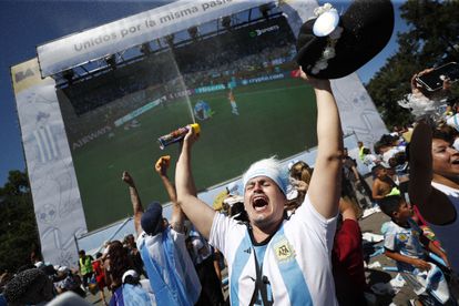 Un hincha festeja la victoria delante una pantalla gigante en Buenos Aires.