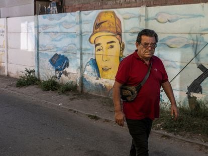 Un adulto camina por un pasaje junto a un mural de un delincuente fallecido en la comuna de Padre Hurtado.