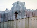 Un hombre sobre el Muro de Berlín contempla la obra de Christo sobre el edificio Reichstag, en junio de 1995.