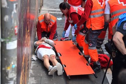 Un corredor es asistido por personal de la Cruz Roja. Seis personas han sido trasladadas a centros hospitalarios, dos de ellas por asta de toro, tras el tercer encierro de San Fermín.