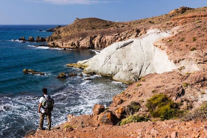 Un senderista se asoma a una de las calas del parque natural de Cabo de Gata-Níjar, en Almería.