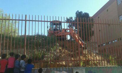 Alumnos del centro observan a la excavadora que destruyó el huerto.