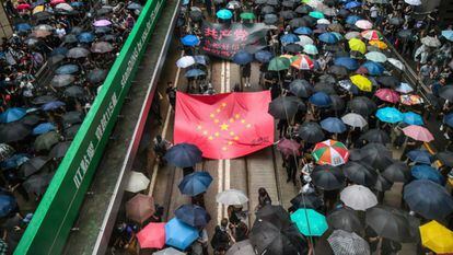 Manifestantes marchan con una pancarta que usa las estrellas de la bandera nacional china para rerpresentar una esvástica nazi. 