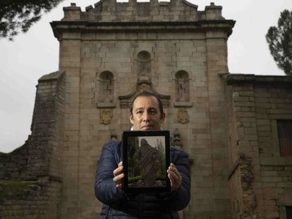 Mario Cuéllar  delante del pórtico del Monasterio de Santa Maria la Real de Valdeiglesias, con la foto de la escultura que ha localizado en una finca en Toledo.