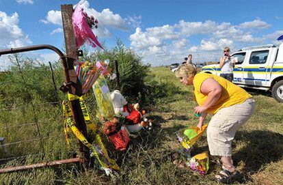 Una seguidora coloca una ramo de flores en un improvisado altar en la verja de la granja donde fue asesinado ayer.