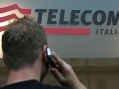 Un hombre habla por el m&oacute;vil ante un logotipo de Telecom Italia.