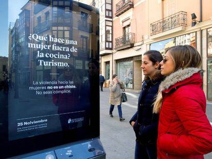 Dos mujeres observan un cartel en Zamora que busca concienciar sobre la violencia machista.