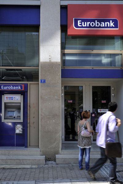 Peatones junto a una oficina de Eurobank, en Atenas.