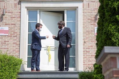 El presidente de la Generalitat, Pere Aragonès, y el expresidente Carles Puigdemont se saludan a la puerta de la residencia de este en Waterloo (Bélgica) antes de la reunión que han celebrado este viernes. 