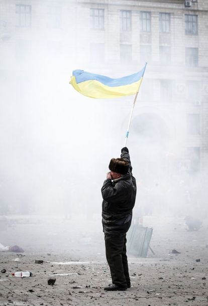 Un manifestante pro europeo agita una bandera, bajo una nube de gas lacrimógeno en el centro de Kiev.