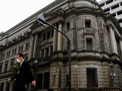 Un hombre con mascarilla cruza un paso de peatones frente a la sede del Banco de Japón en Tokio. 