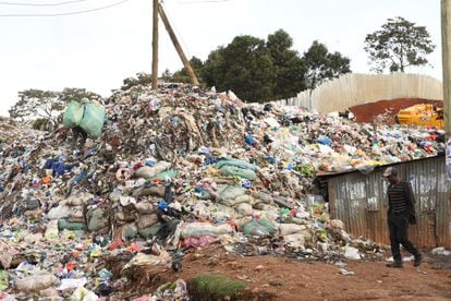 Um homem passa por uma montanha de roupas velhas no depósito de lixo ilegal de Kawangware, em Nairóbi, em 18 de setembro.