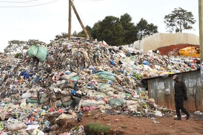 Un hombre camina junto a una montaña de ropa vieja en el vertedero ilegal de Kawangware, en Nairobi, el pasado 18 de septiembre.