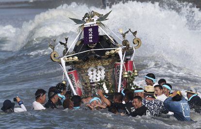 Participantes en el Festival Hamaori llevan un santuario o mikoshi, a través del mar en Chigasaki, al oeste de Tokio.