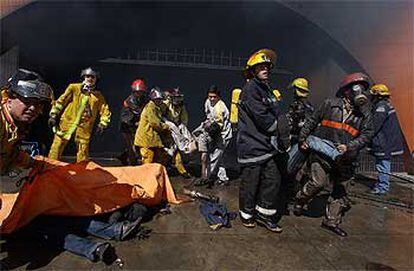 Los bomberos rescatan a las víctimas del incendio en el centro comercial Ikuá Bolaños, a las afueras de Asunción.