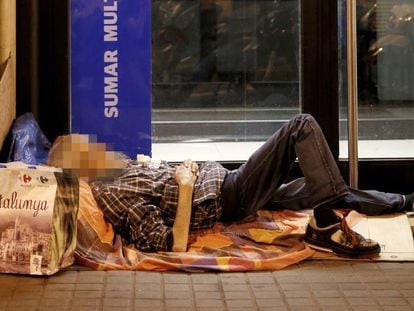 Un sin techo, durmiendo a la intemperie a las puertas de una oficina bancaria en Barcelona.