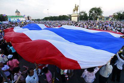 Partidarios progubernamentales ondean una gigantesca bandera tailandesa en una concentración en Bangkok.