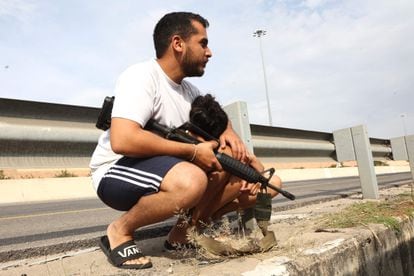 Un israelí armado protege a su hijo después de salir de su vehículo para refugiarse durante un ataque con cohetes desde la franja Palestina de Gaza, a lo largo de una carretera principal en Tel Aviv, este viernes. 