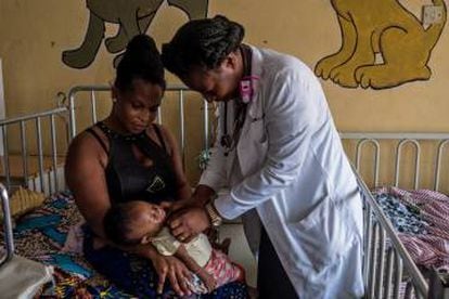 Arriba: El equipo médico del área pediátrica del hospital de Maamobi examina expedientes de enfermos de malaria. Abajo: La doctora Lydia Daytei ausculta a un paciente en el área pediátrica del hospital de Maamobi en Accra, Ghana.