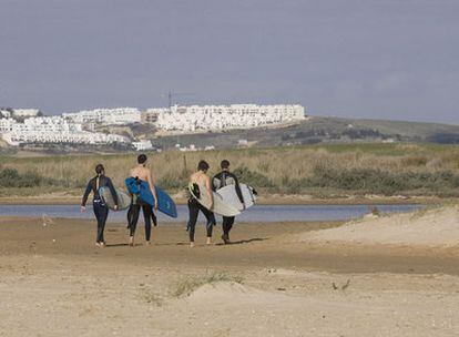 Surfistas pasean frente al paraje de El Palmar donde se proyectan los apartahoteles.