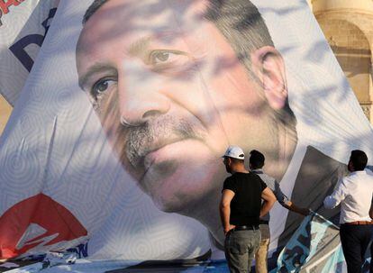 Trabajadores ajustan un poster de Erdogan en Mardin, en el sur de Turquía 