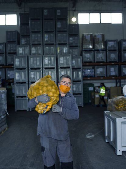 Joaquín García, voluntario del Banco de Alimentos de Cantabria, carga un saco de patatas en el almacén de la asociación en Tanos, Cantabria.