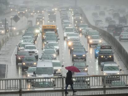Un transeúnte camina con un paraguas mientras conductores conducen a través de la lluvia en Hollywood, Los Angeles, Marzo 10, 2023.