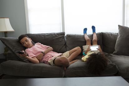 Dos niños aburridos en el sillón de su casa.