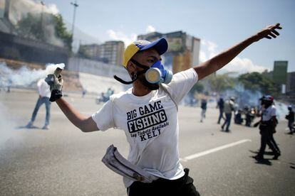 Un manifestante de la oposición arroja una bomba de gas lacrimógeno en una calle cerca de la base aérea La Carlota, en Caracas.