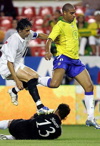 El brasileño Adriano (dcha.) y Pablo Alfaro saltan por encima del portero sevillista Notario.