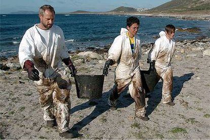 Tres voluntarios recogían ayer fuel incrustado en las rocas en la costa de Carnota (A Coruña).