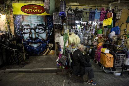 El dueño de una tienda espera la llegada de clientes junto a un grafiti que representa al director de cine estadounidense Steven Spielberg.