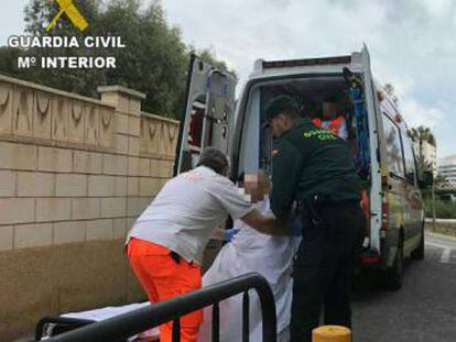 Un sanitario y un agente de la Guardia Civil trasladan el cad&aacute;ver de la mujer.