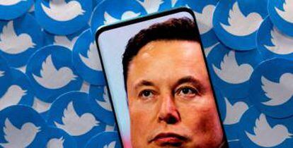 Una imagen de Elon Musk en un smartphone sobre logos impresos de Twitter.