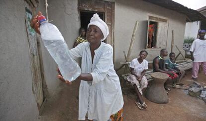 Una mujer se lava las manos con agua clorada, una medida de prevención ante el ébola, en Sierra Leona