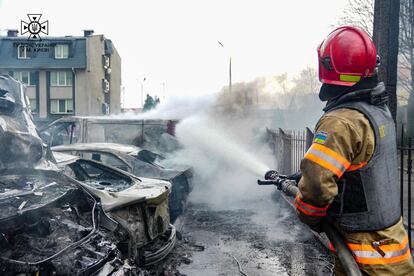 Un bombero apaga las llamas de un vehículo alcanzado por fragmentos de un misil, este jueves en Kiev.