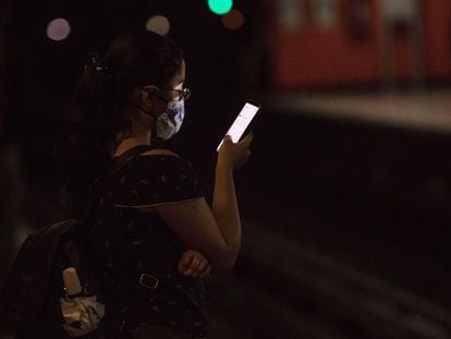 Una mujer usa su teléfono móvil mientras espera la llegada del Metro en Ciudad de México.
