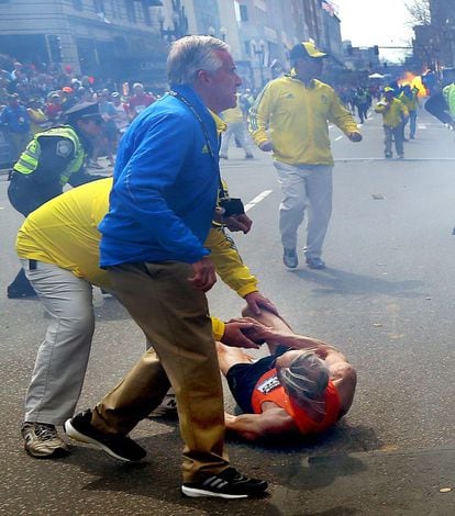  Bill Iffrig, de 78 a&ntilde;os es ayudados a levantarse momentos despu&eacute;s de la primera explosi&oacute;n.