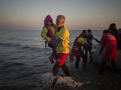 Enrique Álvarez ayuda el lunes a bajar a una niña refugiada en una playa cercana a la ciudad de Mytilene, en la isla de Lesbos.