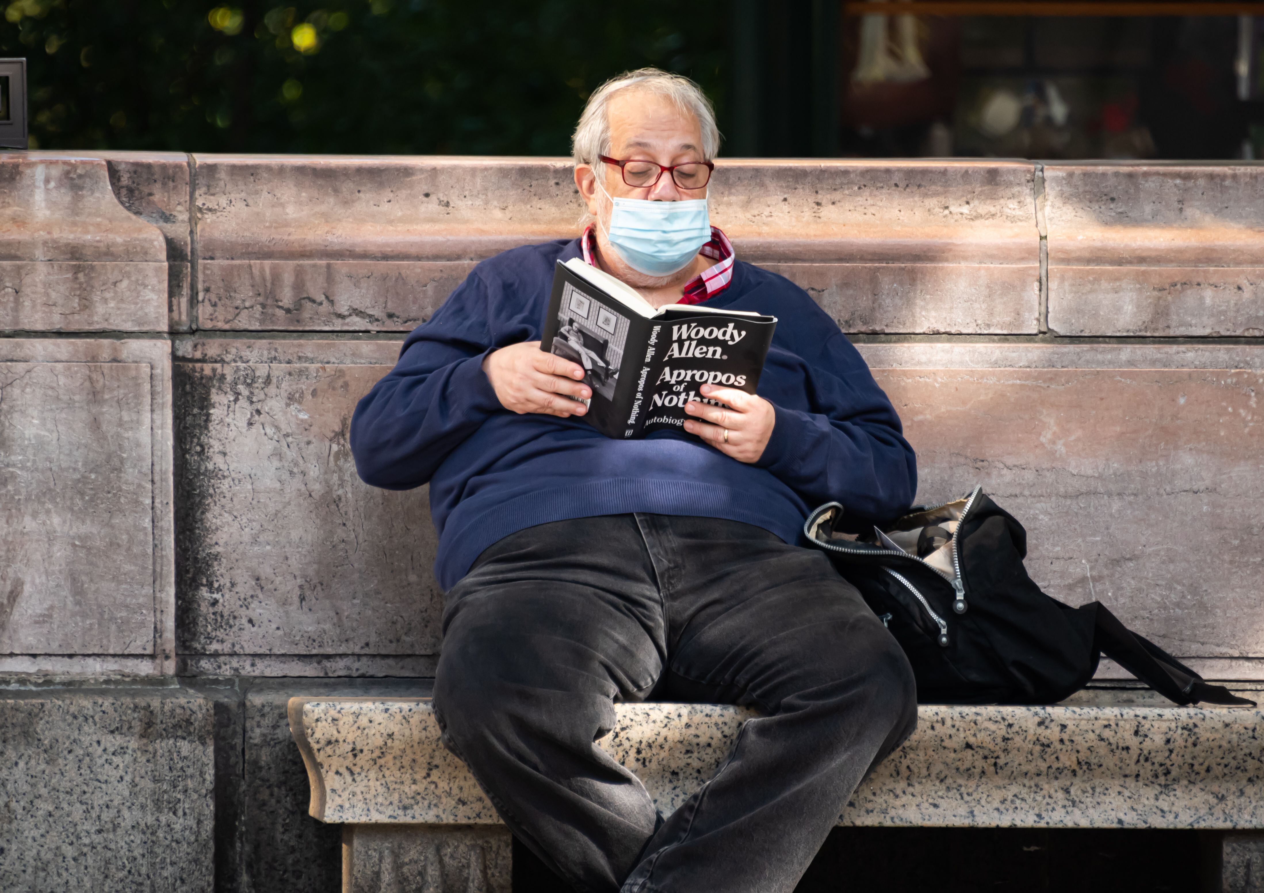 Un hombre lee en un parque, con mascarilla como mandaba el año 2020, las memorias de Woody Allen en Nueva York.