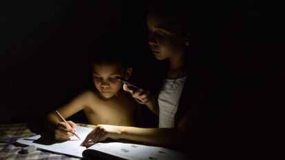 Dos niños estudian con la luz de un móvil en Maracaibo (Venezuela), el 21 de abril de 2019.